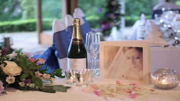 A table set with a bottle of champagne, shot glasses, a framed photo, and a candle.