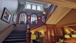 A grand staircase with wooden balusters, a chandelier, and a view of the upper floor through arched windows. - Invercarse Hotel Dundee, BW Signature Collection (Dundee)