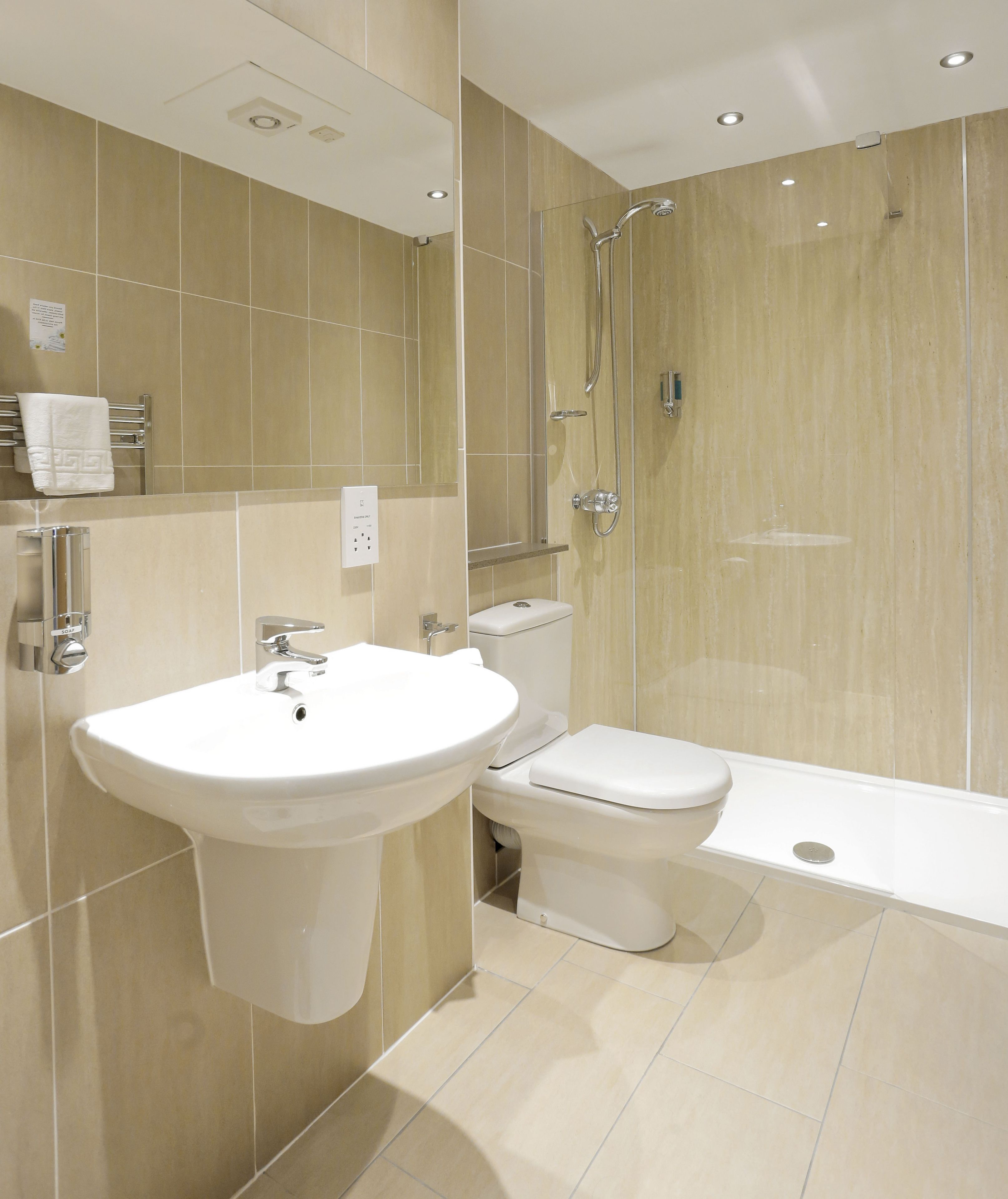 Un baño moderno con lavamanos, inodoro y ducha.