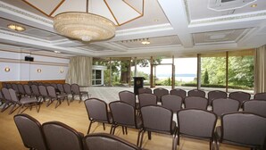 A conference room with rows of chairs, a podium, and large windows with a view.