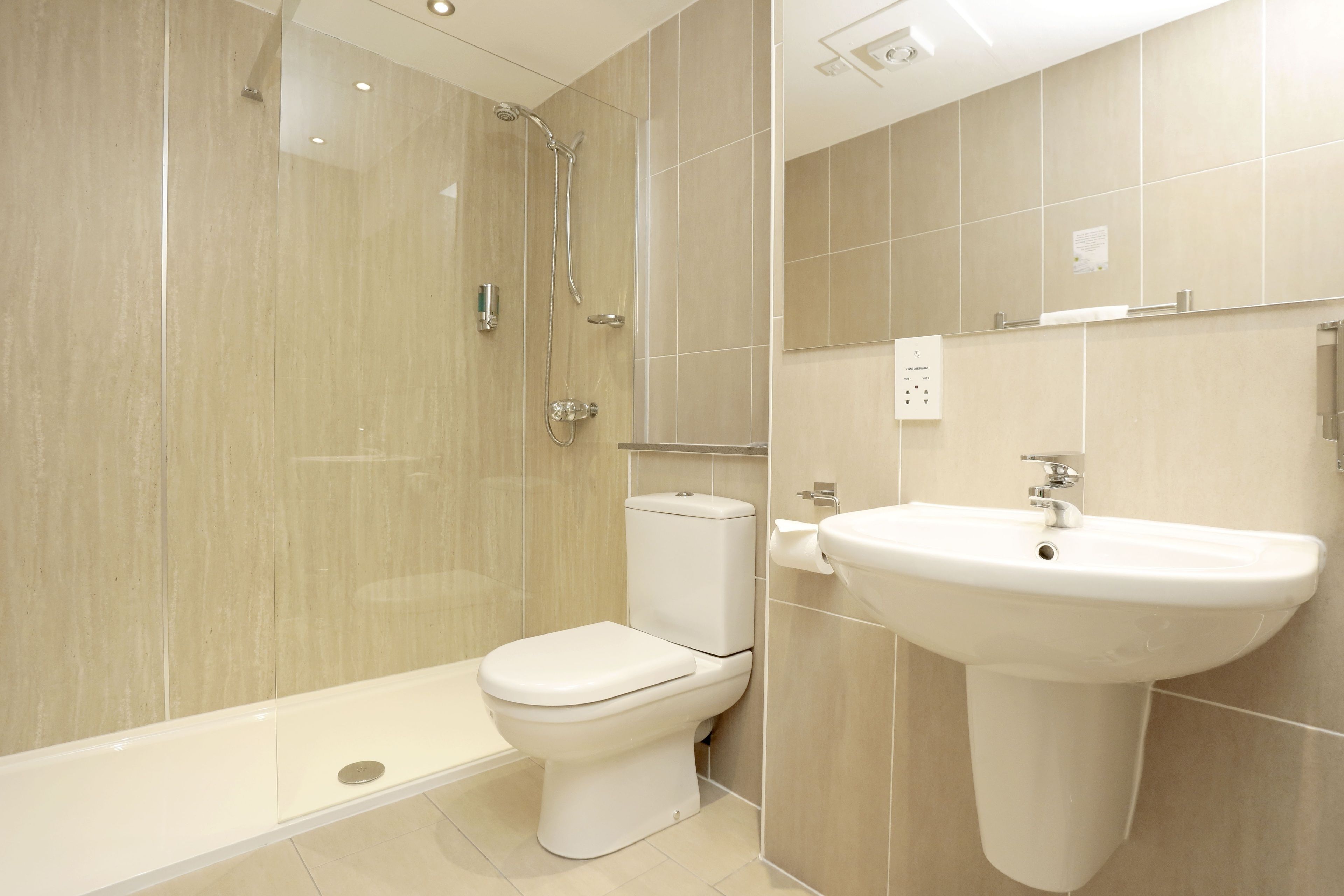 A modern bathroom with a shower, toilet, and sink.