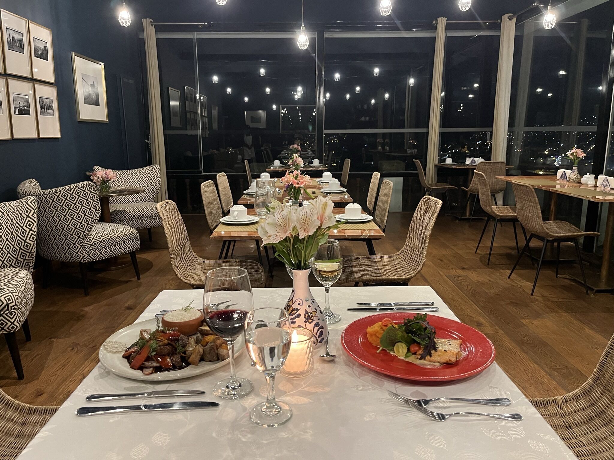 A dining area with tables set for two, featuring a variety of dishes and drinks.