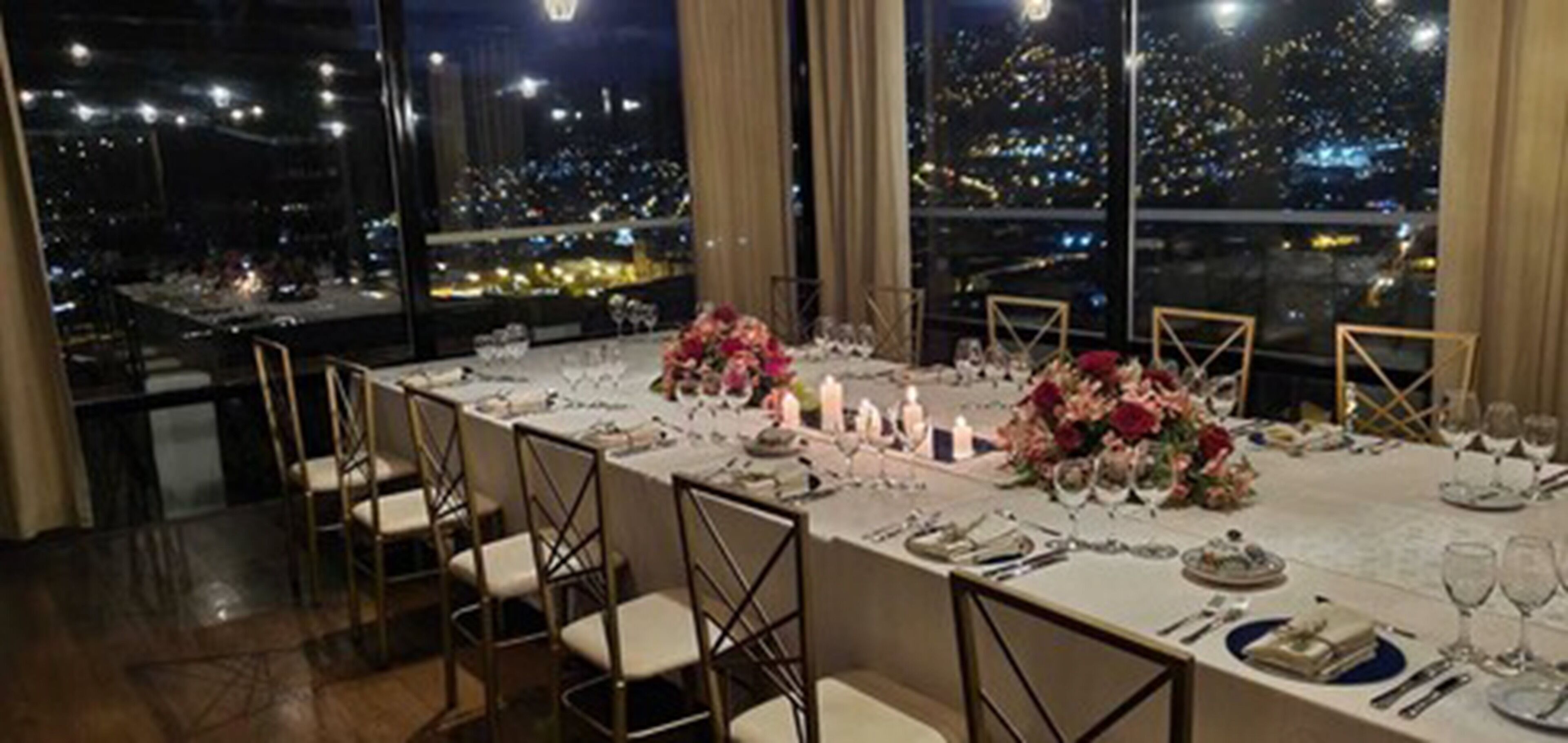 Una mesa de comedor lista para una comida, con sillas, velas y flores.