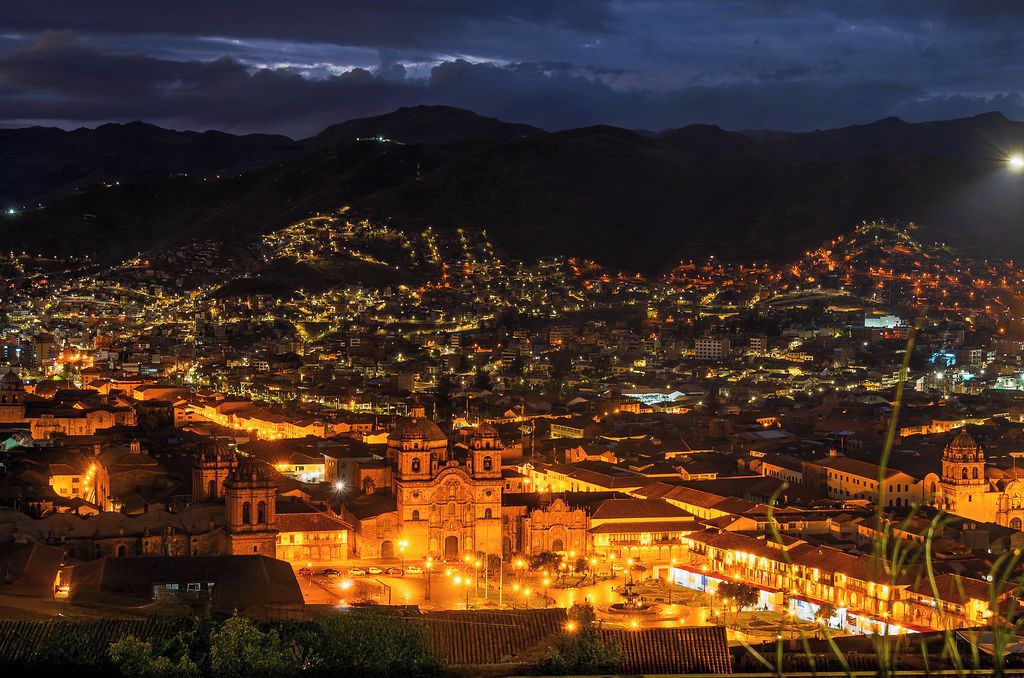 A cityscape at night with illuminated buildings and a prominent church with a dome.