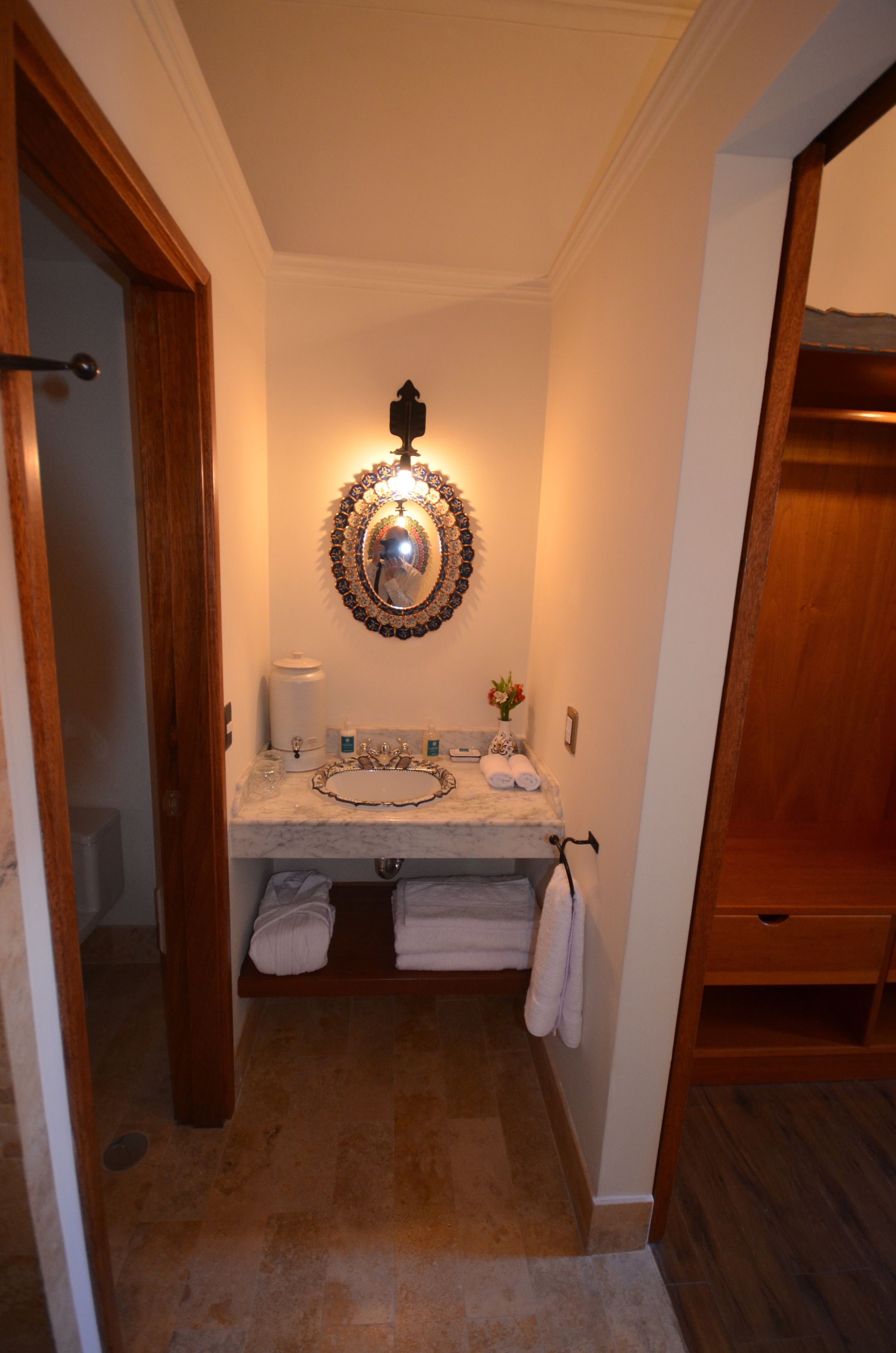 A bathroom with a marble sink, a decorative mirror, and a towel rack.