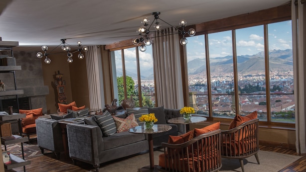 A spacious living room with a large window offering a city view, a fireplace, and modern furniture. - Palacio Manco Capac by Ananay Hotels (Cusco)