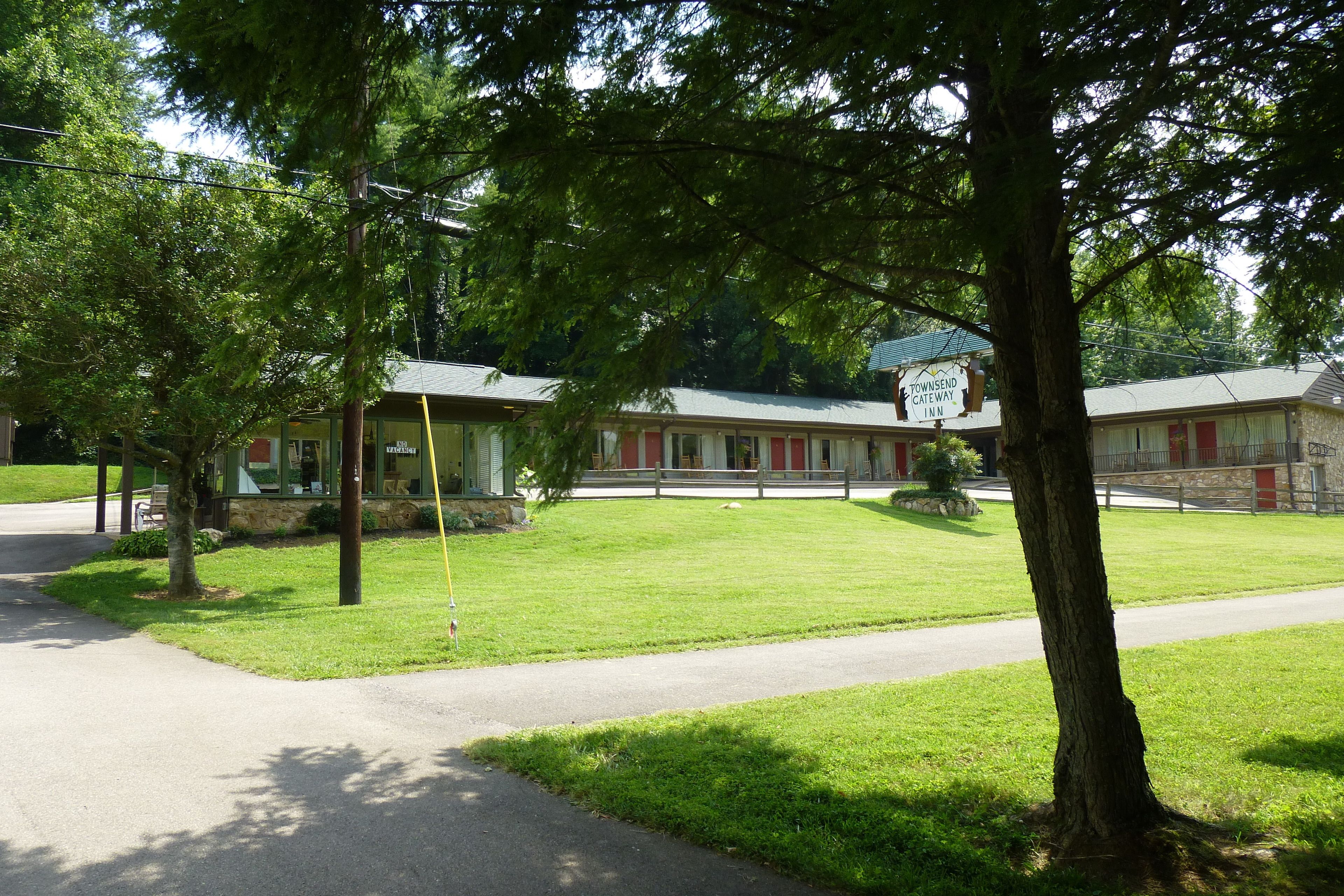 Un motel con césped verde, camino pavimentado y un letrero que dice Townsend Gateway Inn.