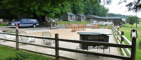 Een camping met buitenterras, een buitenkraan en een grote boom.