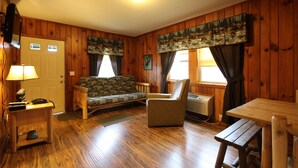 A wooden-furnished room with a sofa, armchair, and table. - Townsend Gateway Inn (Townsend)