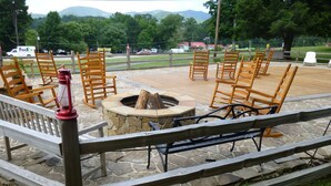 An outdoor patio area with wooden chairs and a stone fire pit. - Townsend Gateway Inn (Townsend)