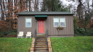 A small house with a red door, a front porch with two chairs, and a stone staircase leading to the door. - Townsend Gateway Inn (Townsend)