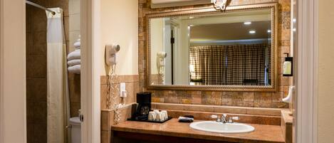 A bathroom with a sink, mirror, and hairdryer. There is a shower curtain and a towel rack.