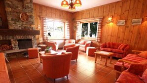 Una habitación acogedora con chimenea de piedra, paredes de madera y un sofá rojo.