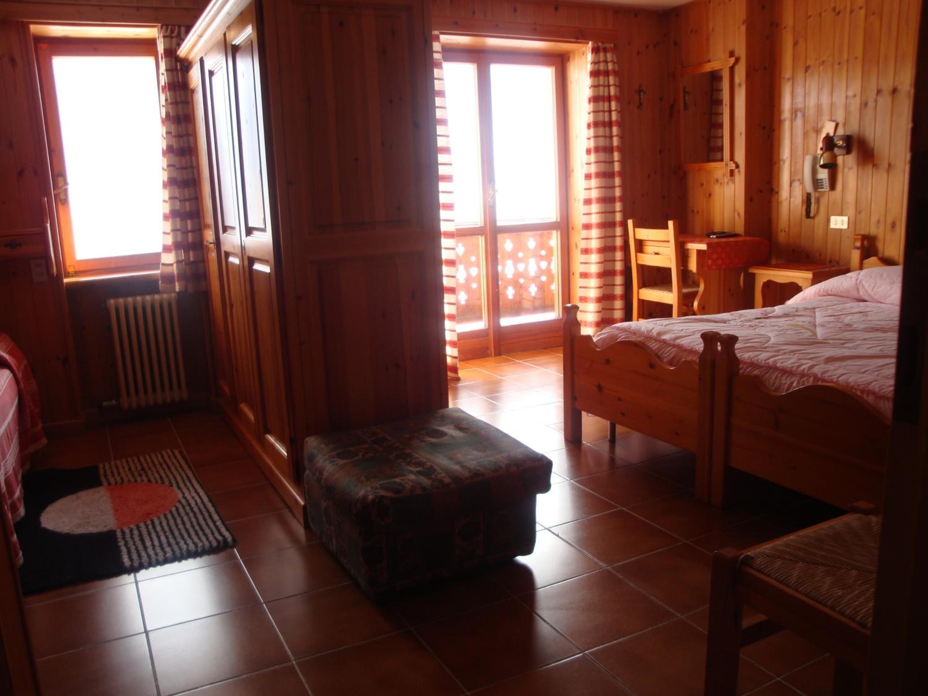 Una habitación de madera con una cama, una silla, una mesita y un radiador.