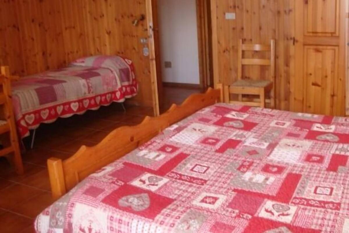 A wooden room with a bed and a small table.