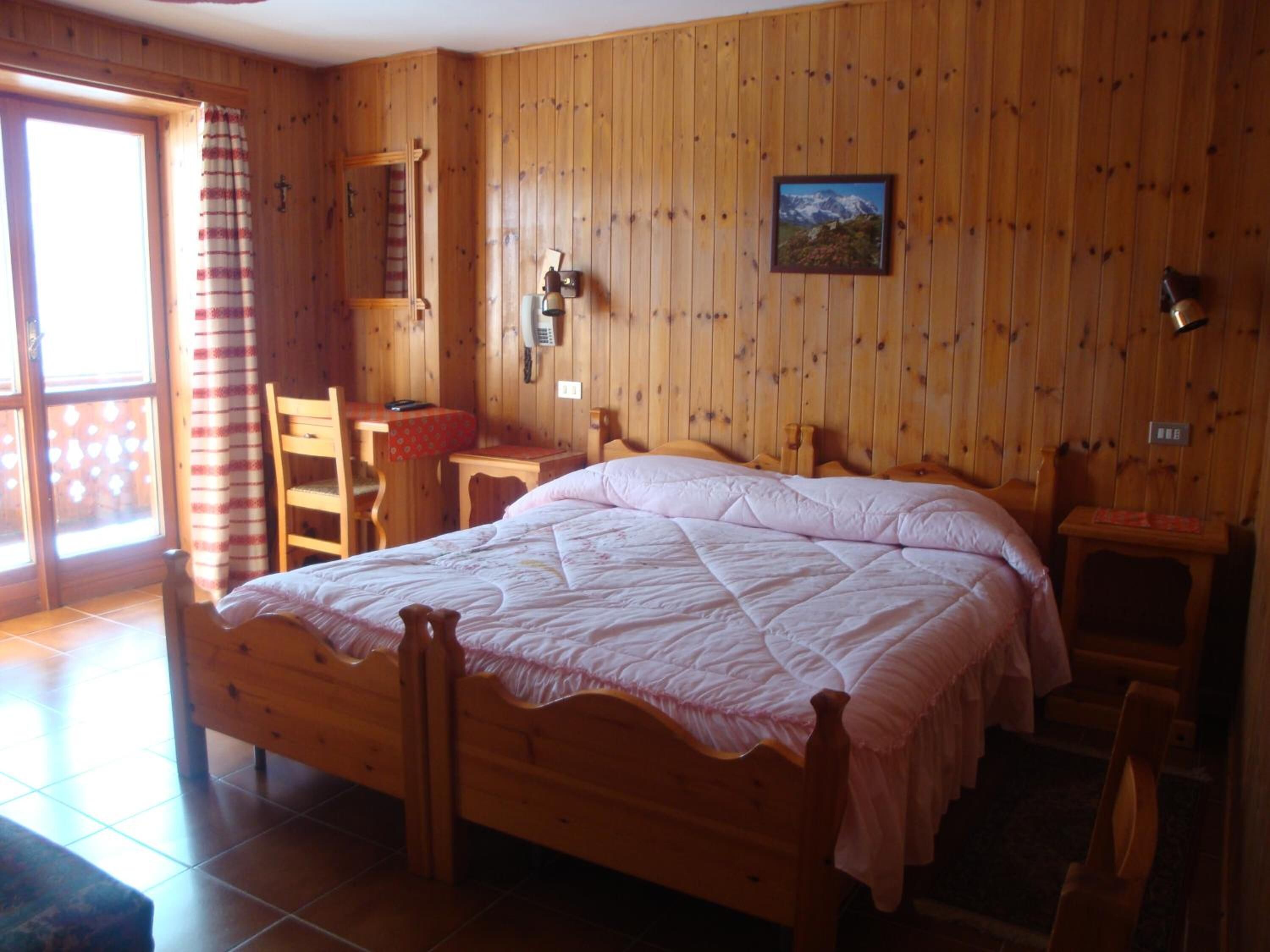 Una stanza con rivestimento in legno, un letto grande, una scrivania e una sedia.