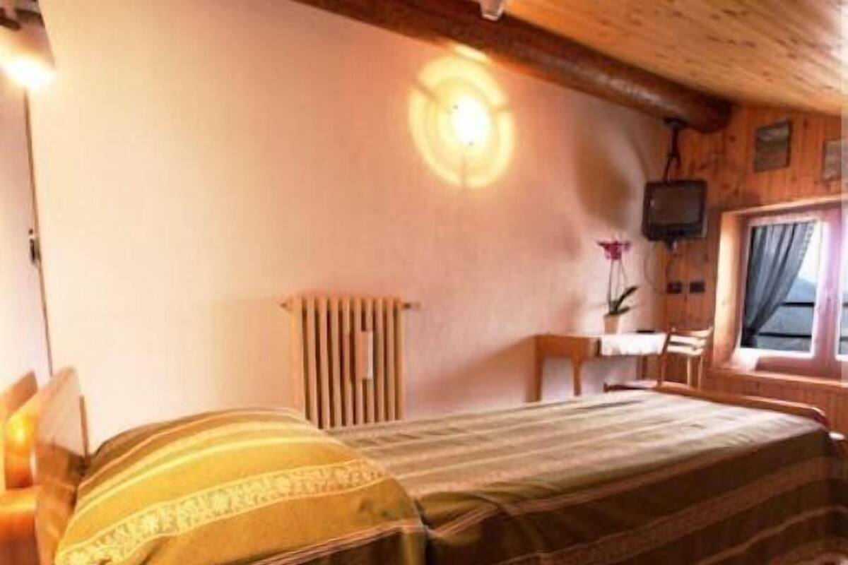 A cozy bedroom with a bed, a desk, and a radiator.