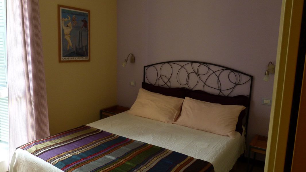 A neatly made bed with a striped bedspread, a headboard with a circular design, and a framed picture on the wall.