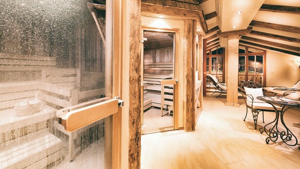 A wooden interior with a staircase, a dining area with chairs, and a view through a door. - Berg-Leben (Grossarl)