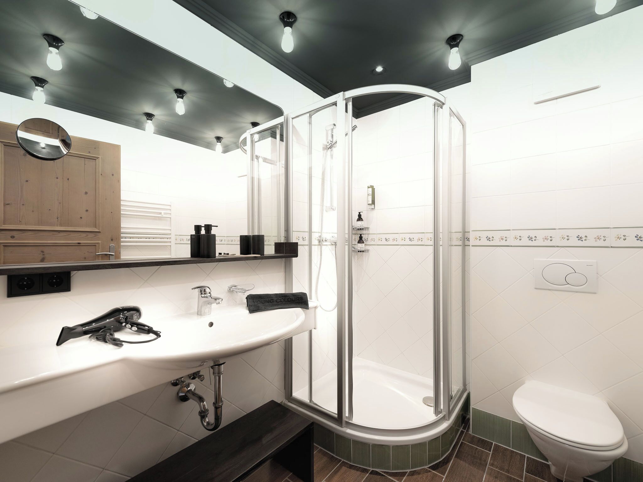 A modern bathroom with a glass-enclosed shower, a white sink with a mirror, and a toilet.