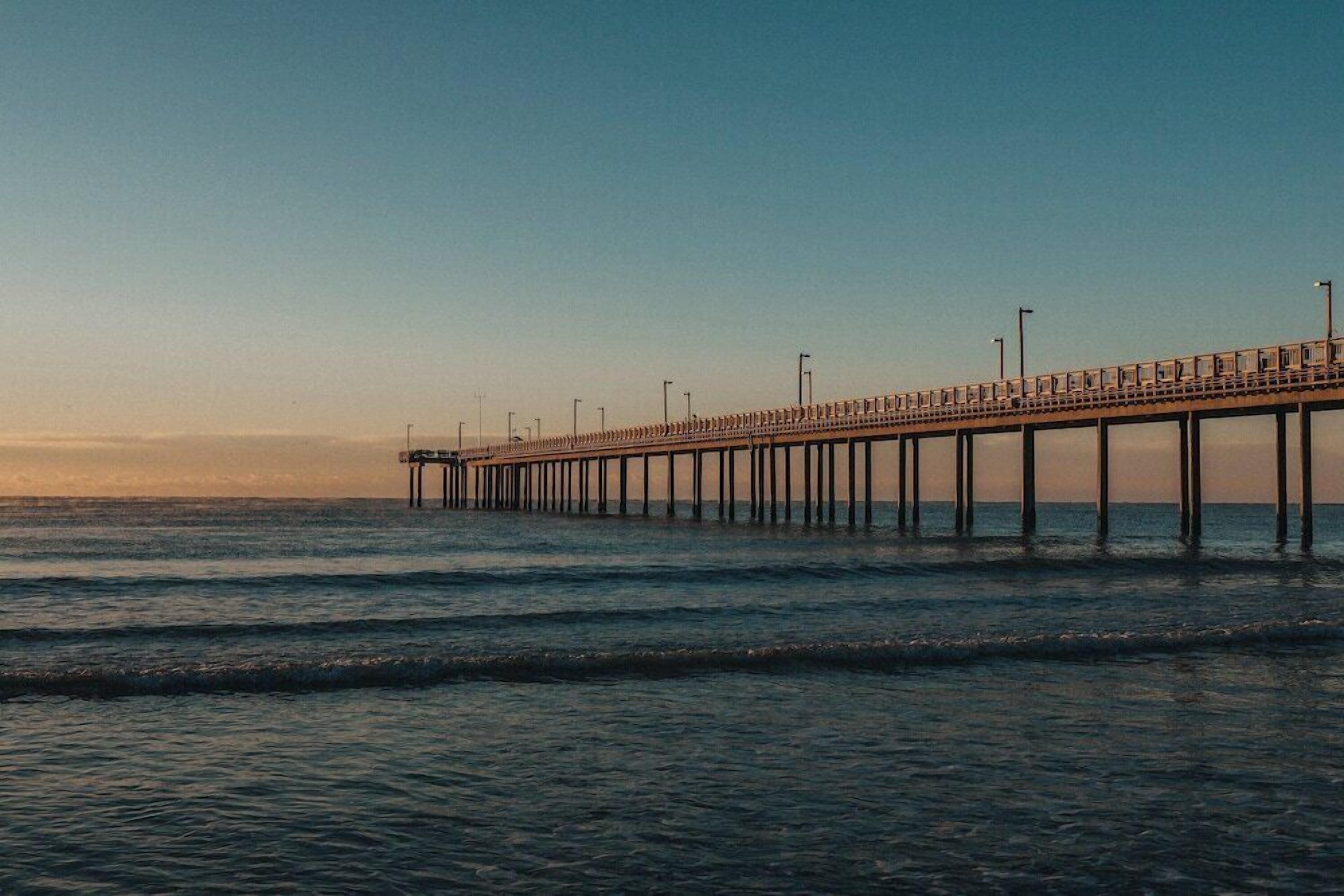 A pier extending into the water with a clear sky above.