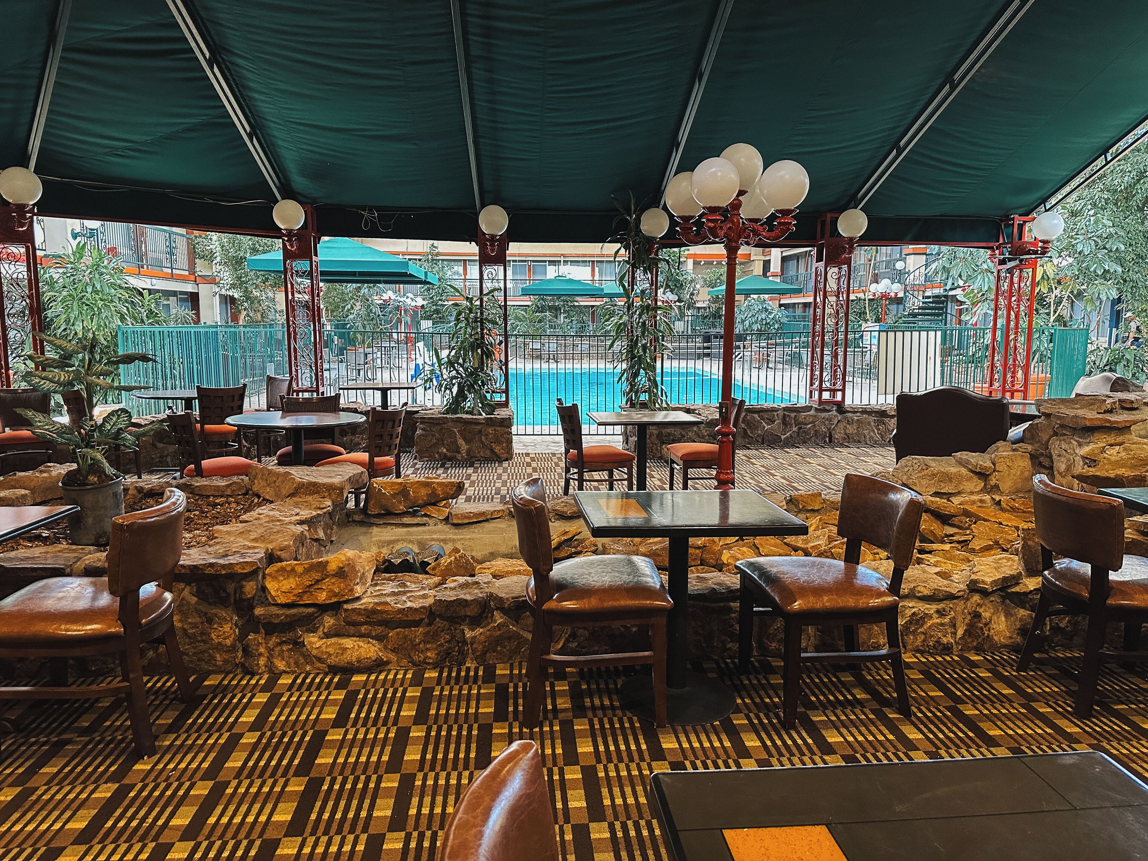 Un restaurant en plein air avec des murs et des tables en pierre, donnant sur une piscine.