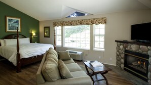A bedroom with a four-poster bed, a sofa, a fireplace, and large windows.