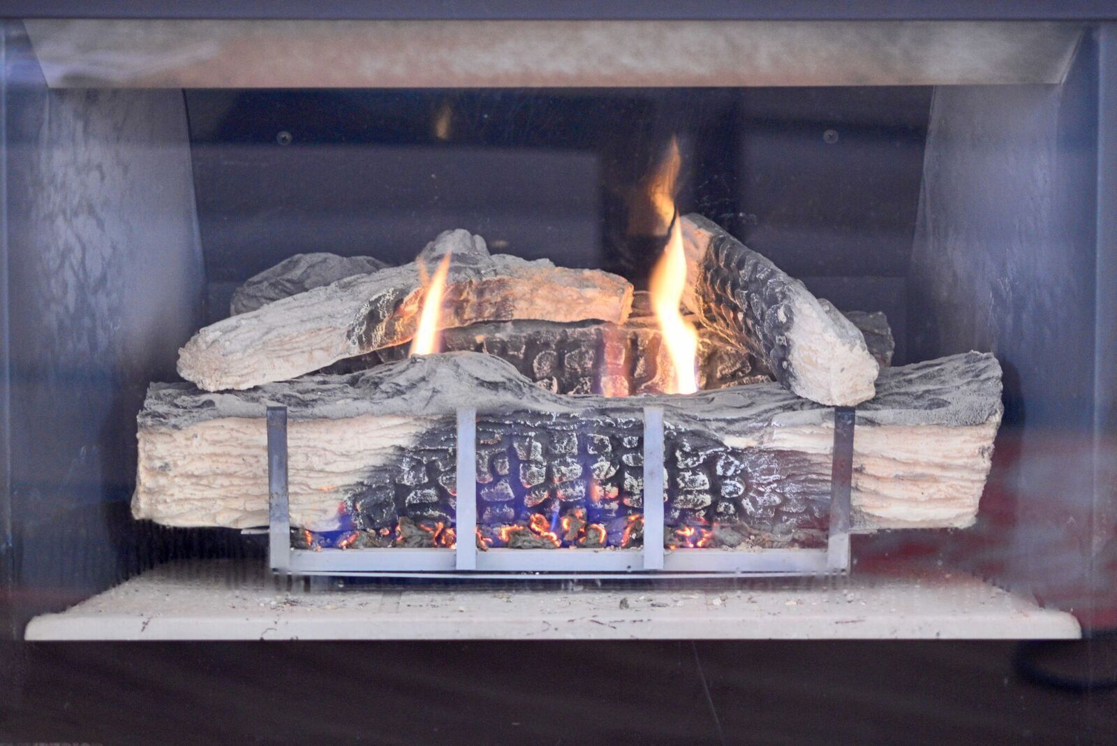 A fireplace with burning logs and a metal grate.