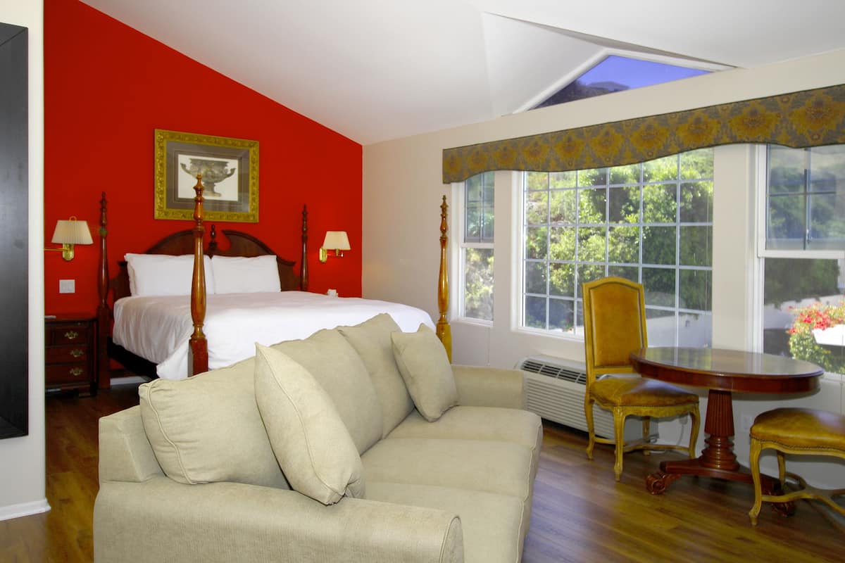 A hotel room with a bed, a sofa, a dining table, and a chair.