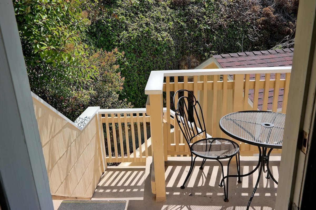A balcony with a wooden fence, two metal tables, and chairs.