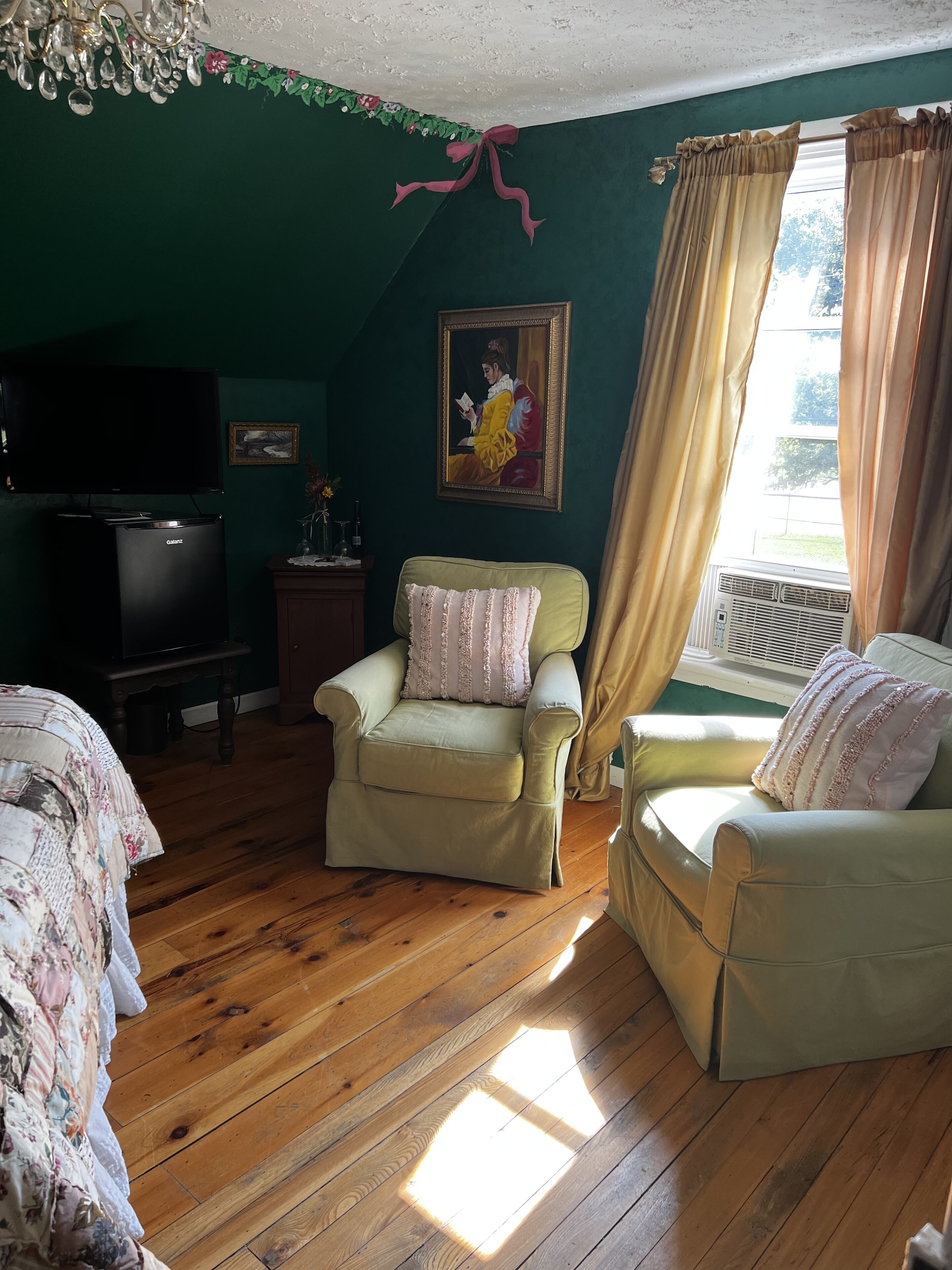 Una habitación con dos sillones, un televisor, un cuadro y un ventanal con cortinas.