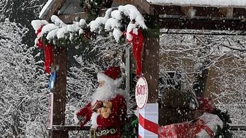Un espacio exterior cubierto de nieve con una estructura de madera, un letrero que dice 'North Pole' y una decoración con forma de bastón de caramelo.