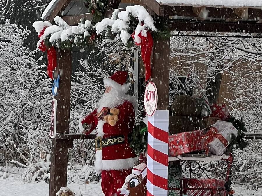 Un espacio exterior cubierto de nieve con una estructura de madera, un letrero que dice 'North Pole' y una decoración con forma de bastón de caramelo.