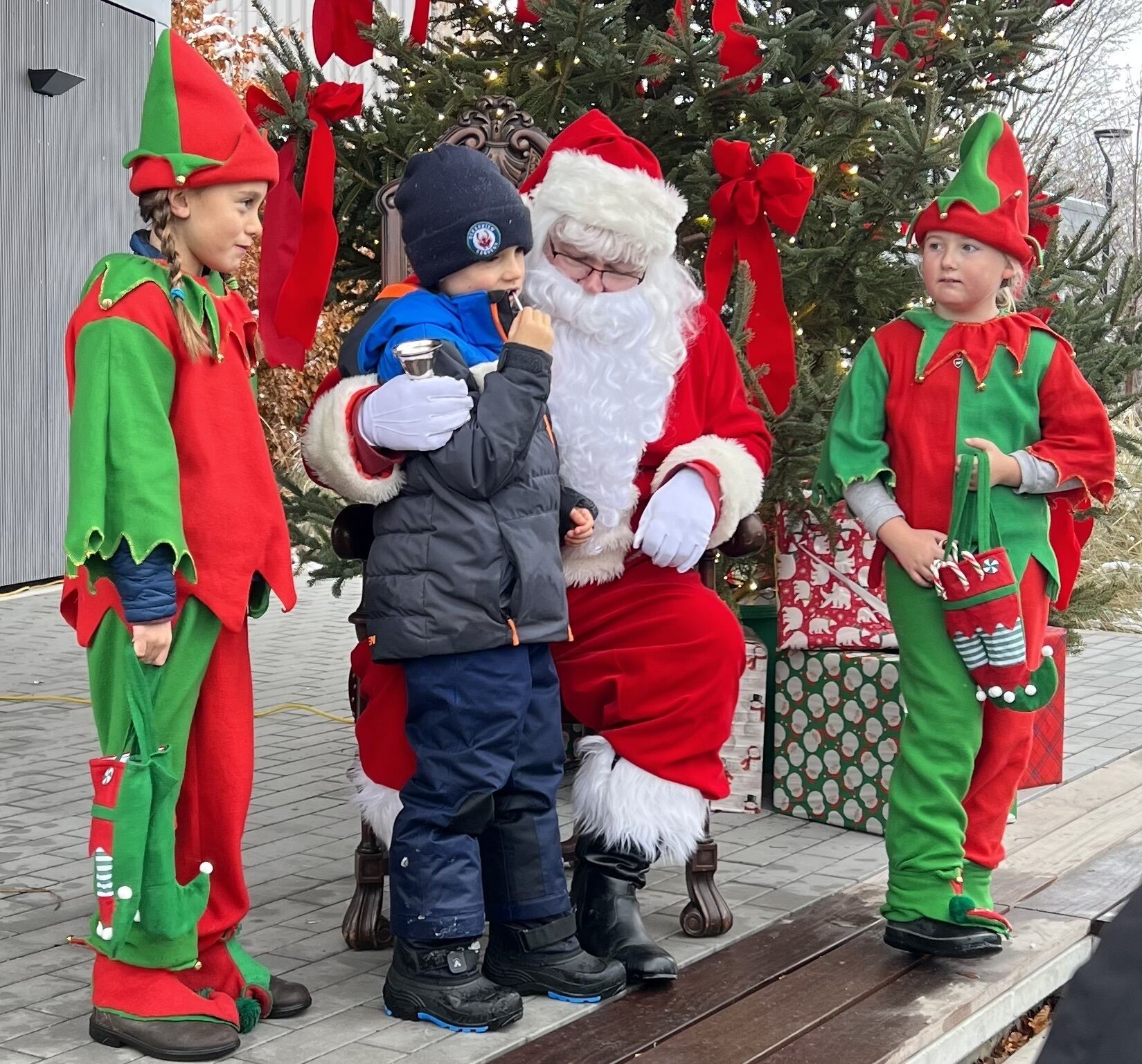 A group of people in festive costumes near a decorated Christmas tree.