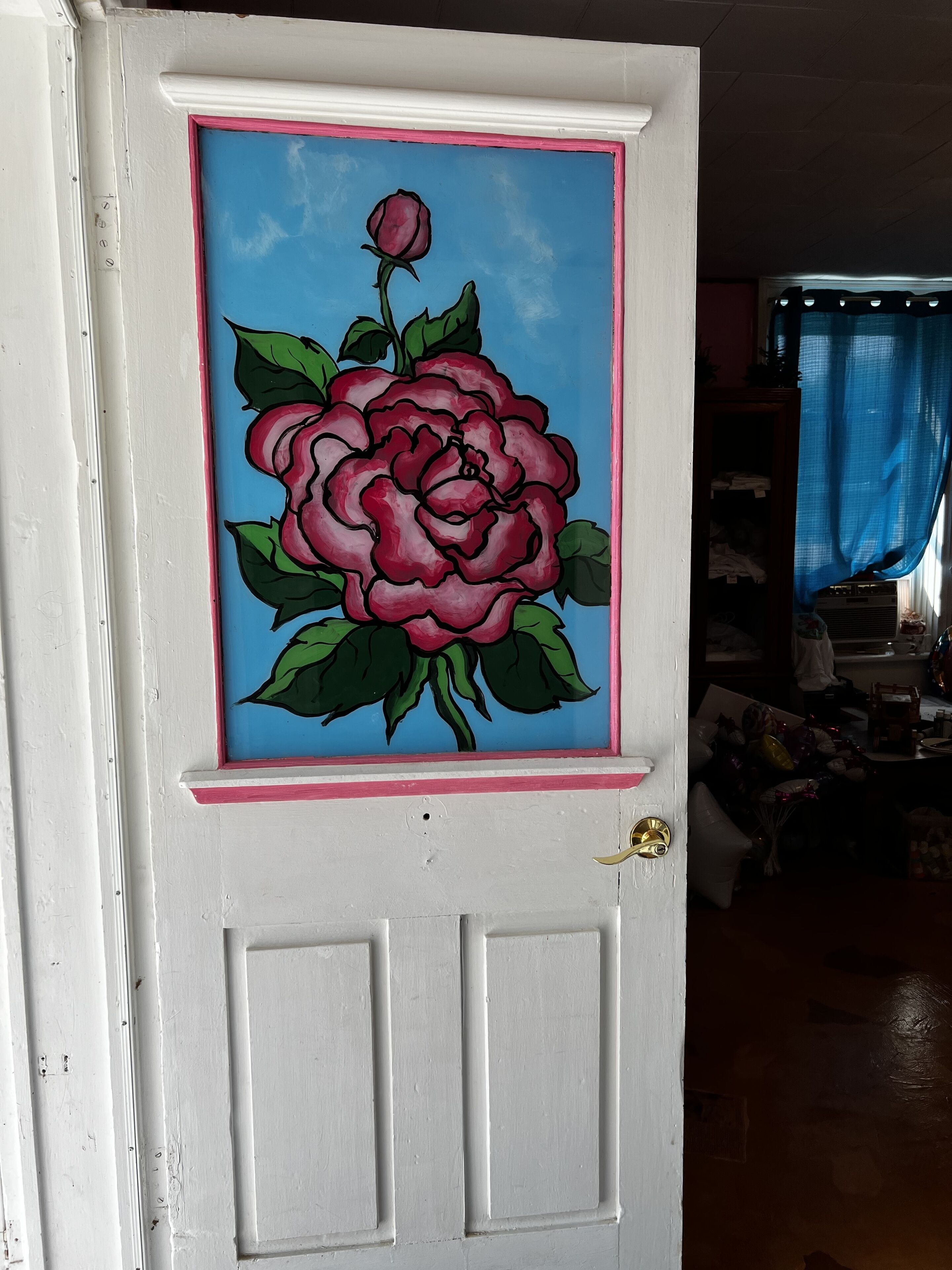Une porte blanche avec un cadre rose et un motif de rose peint.