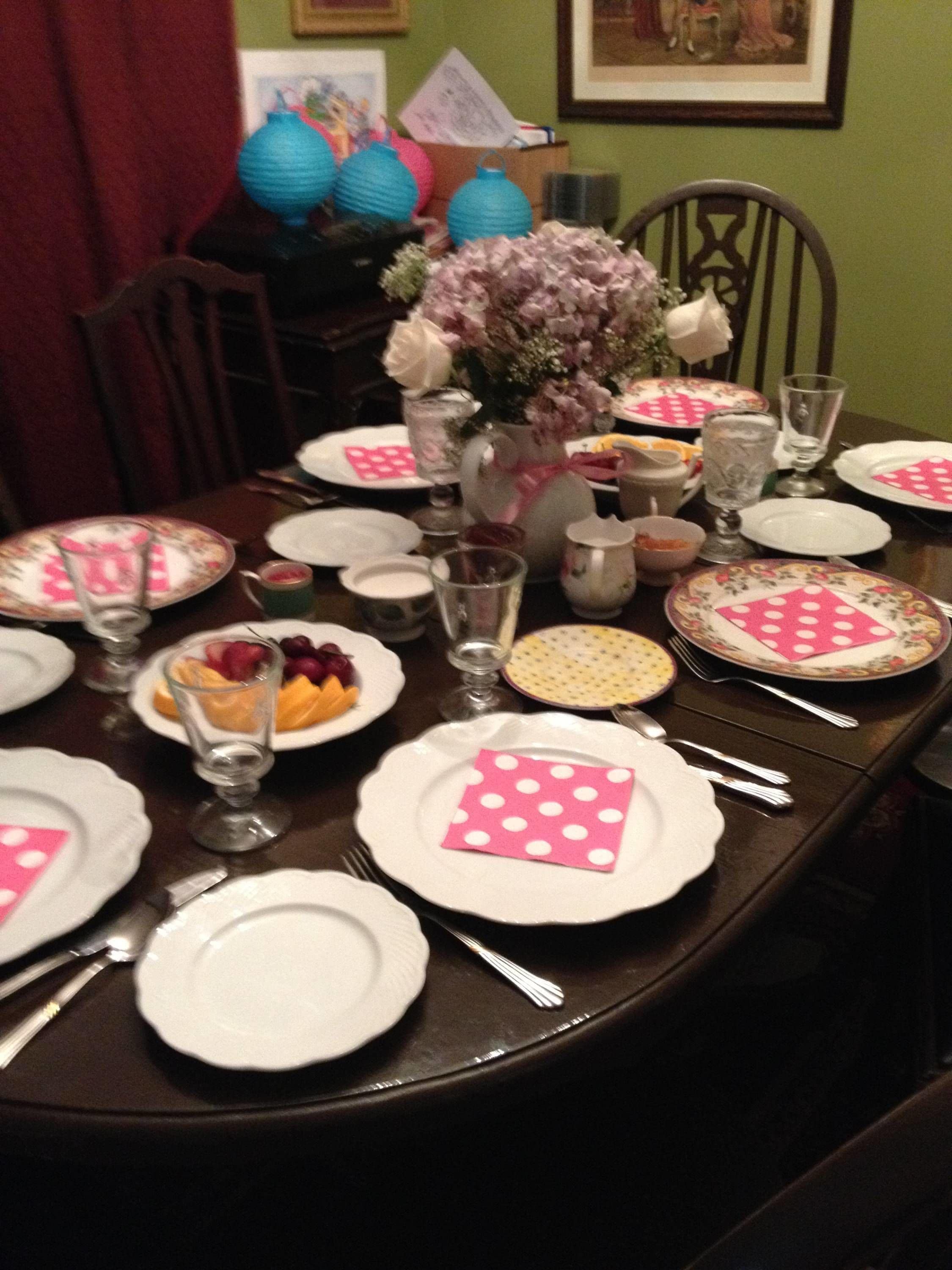 A dining table set with plates, cutlery, and a vase with flowers.