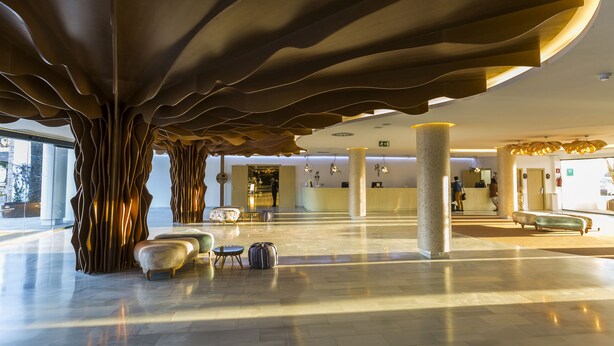 A spacious lobby with a unique ceiling design, comfortable seating, and a reception area. - Grand Palladium White Island Resort & Spa - All Inclusive (Sant Josep de sa Talaia)