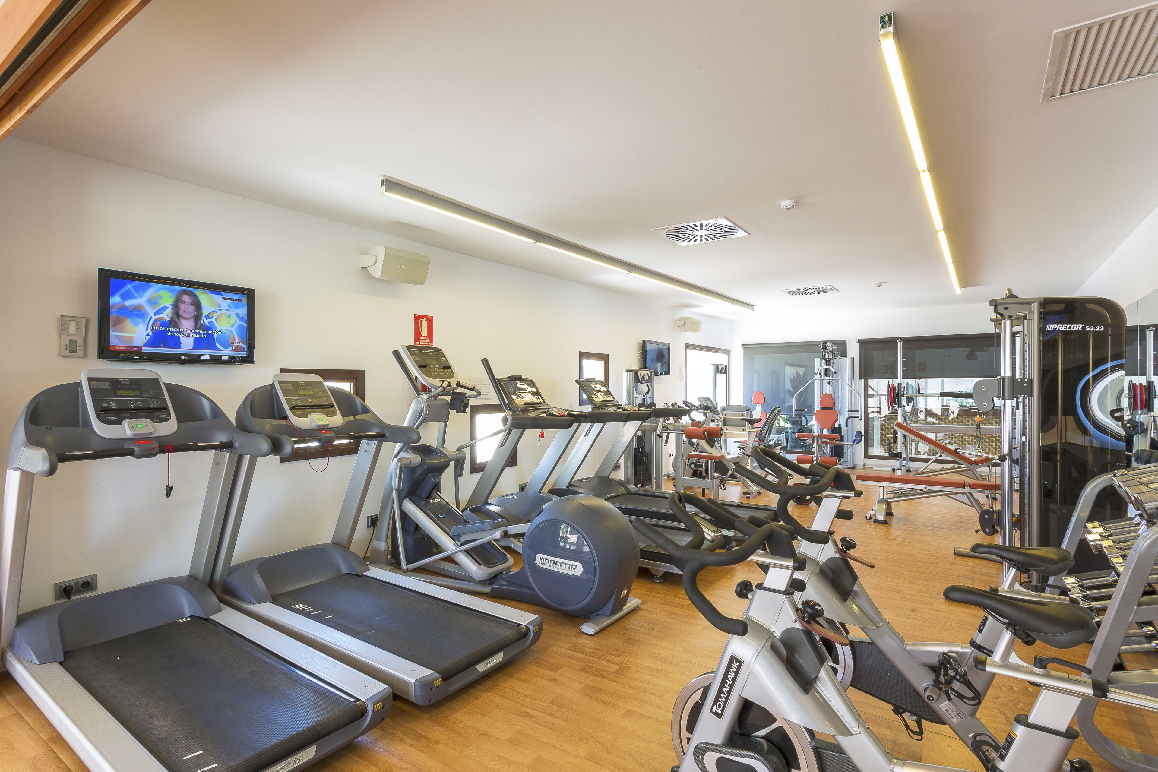 Une salle de sport équipée de tapis de course, de vélos elliptiques et d'appareils de musculation.