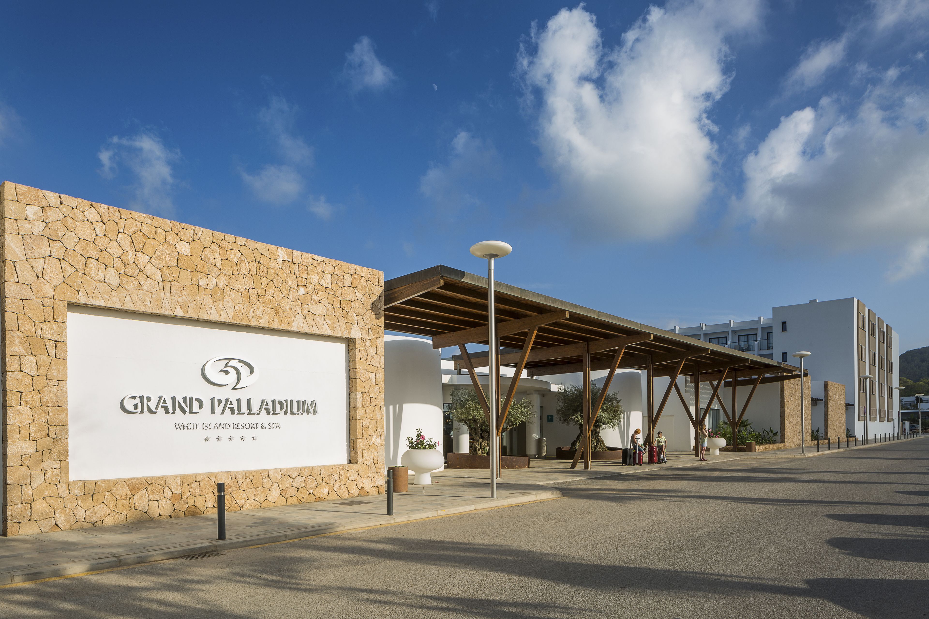 A hotel entrance with a stone facade, a covered walkway, and a clear sky.