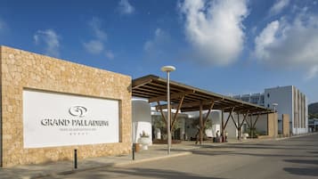 A hotel entrance with a stone facade, a covered walkway, and a clear sky.