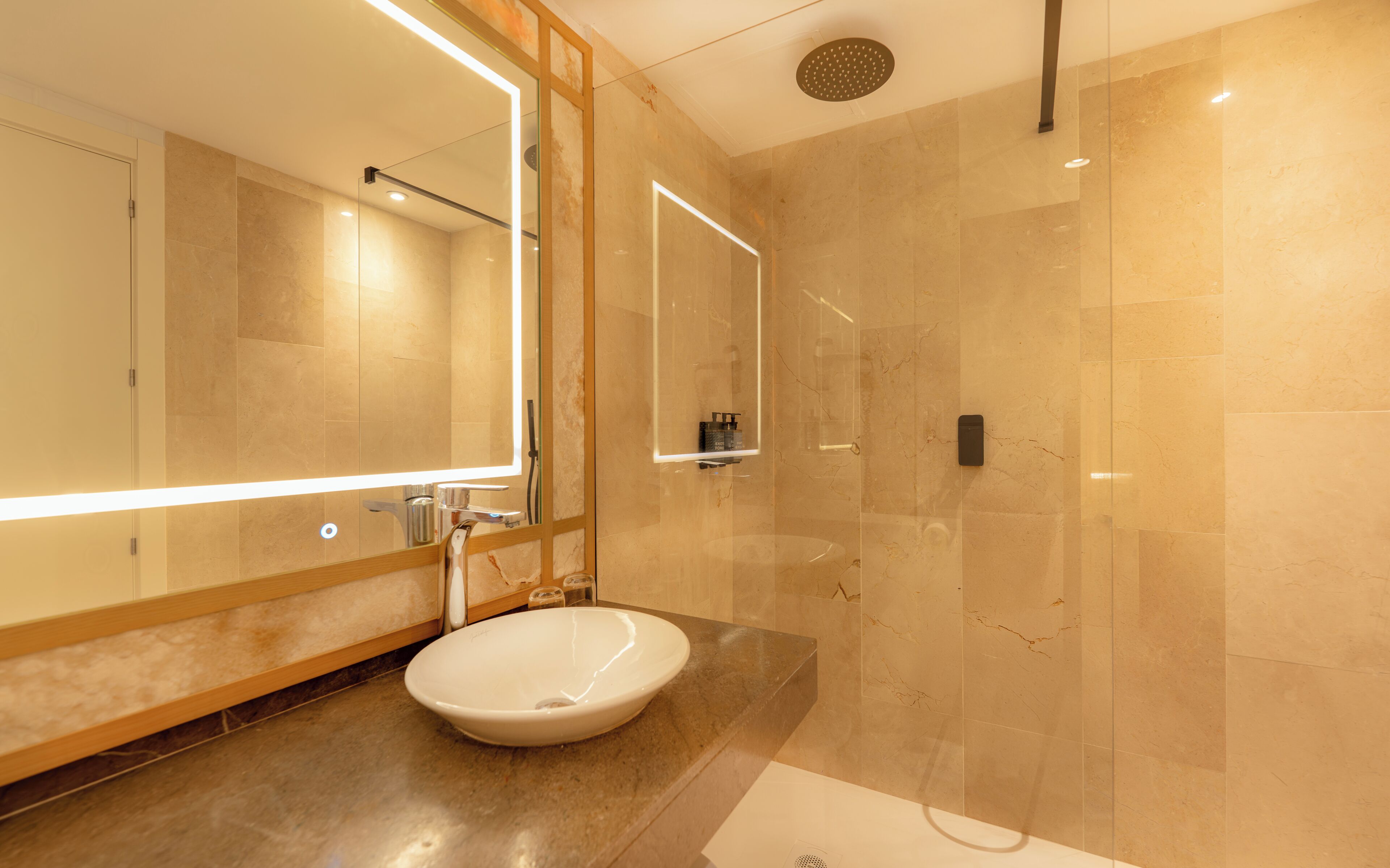 Un baño moderno con un espejo grande, un lavamanos y una ducha.