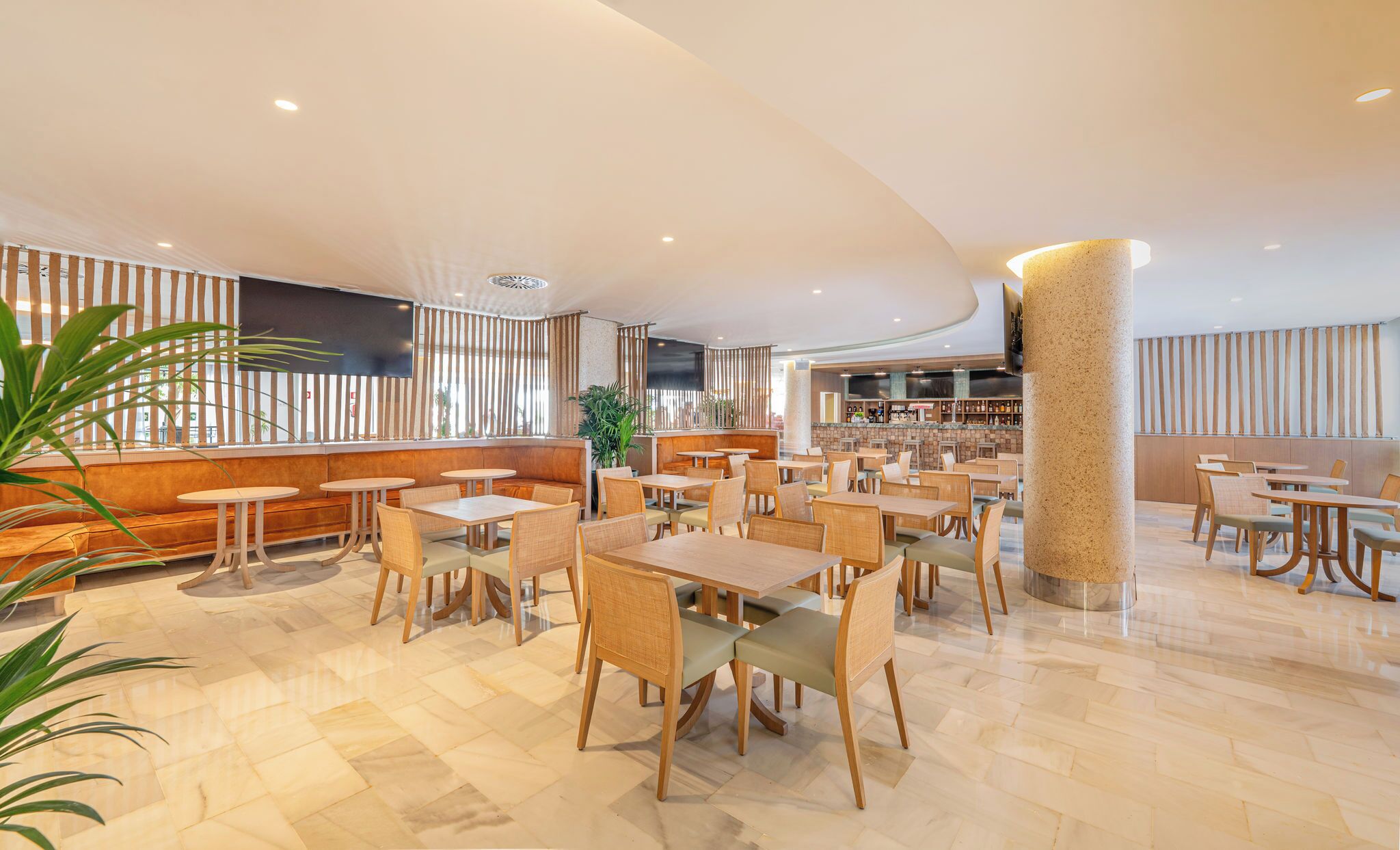 A spacious restaurant with multiple seating areas, including booths and tables. There is a bar area in the background.