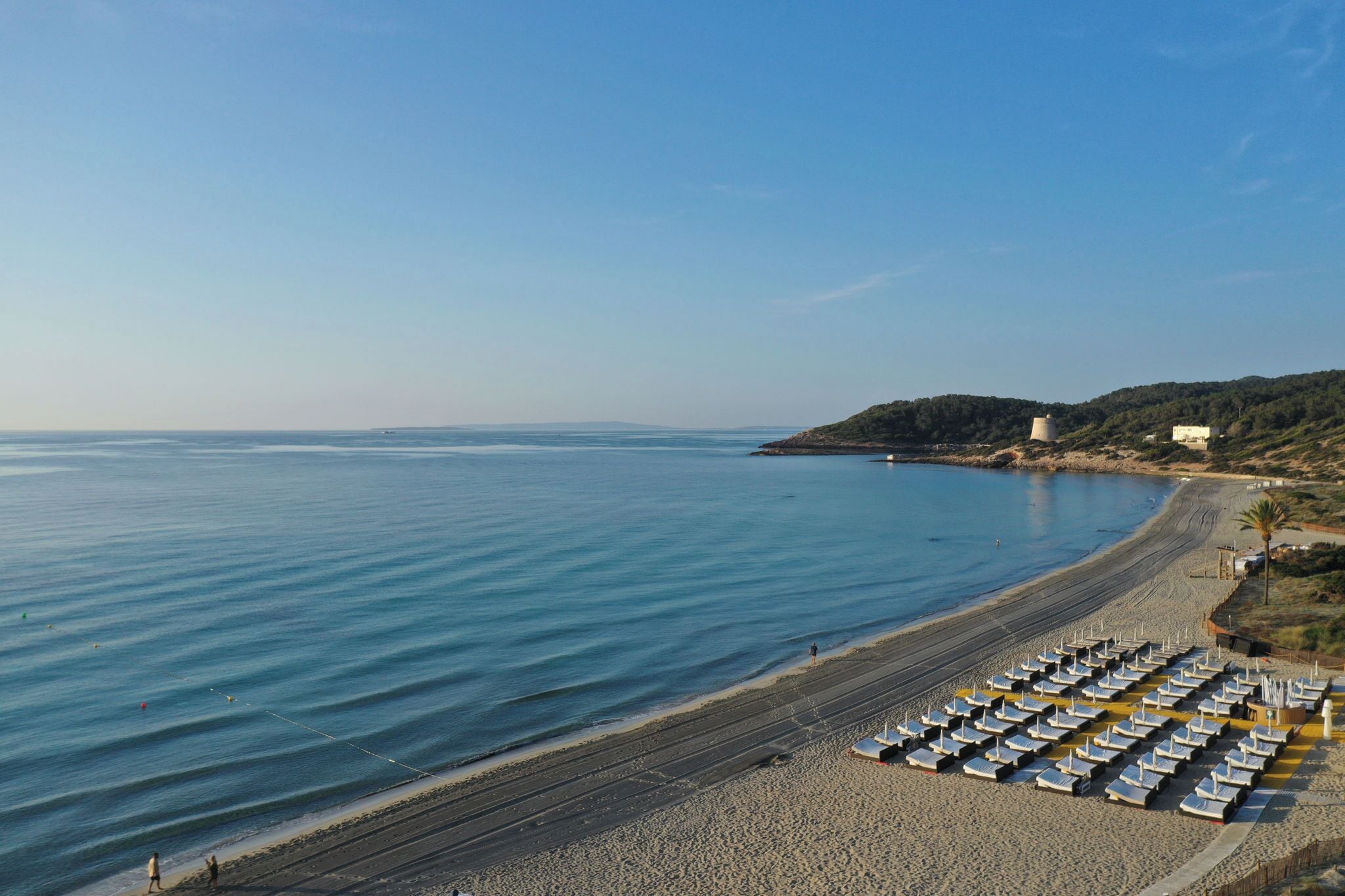 A beach with rows of sun loungers and a clear view of the sea.
