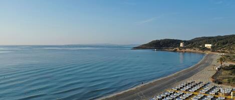 A beach with rows of sun loungers and a clear view of the sea.