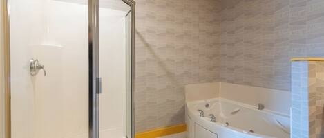 Een badkamer met een douchecabine van glas, een badkuip en een toilet.