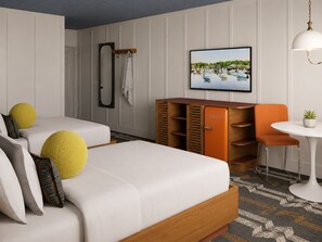 A hotel room with two beds, a TV, a small table with a chair, and a wardrobe.