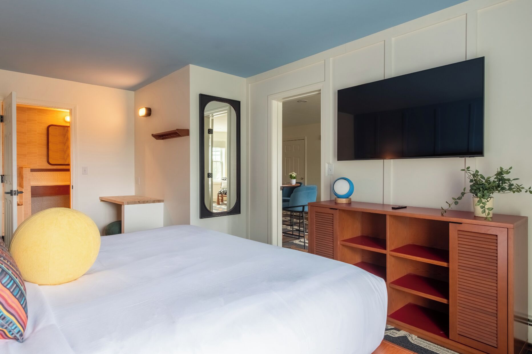Un dormitorio con cama, televisor, espejo y aparador de madera.