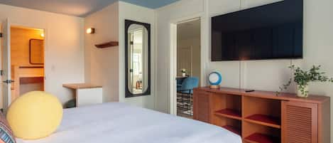 Un dormitorio con cama, televisor, espejo y aparador de madera.