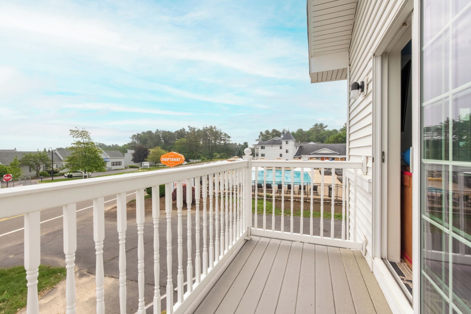 A balcony with a white railing, a pool in the background, and a sign for Driftaway.