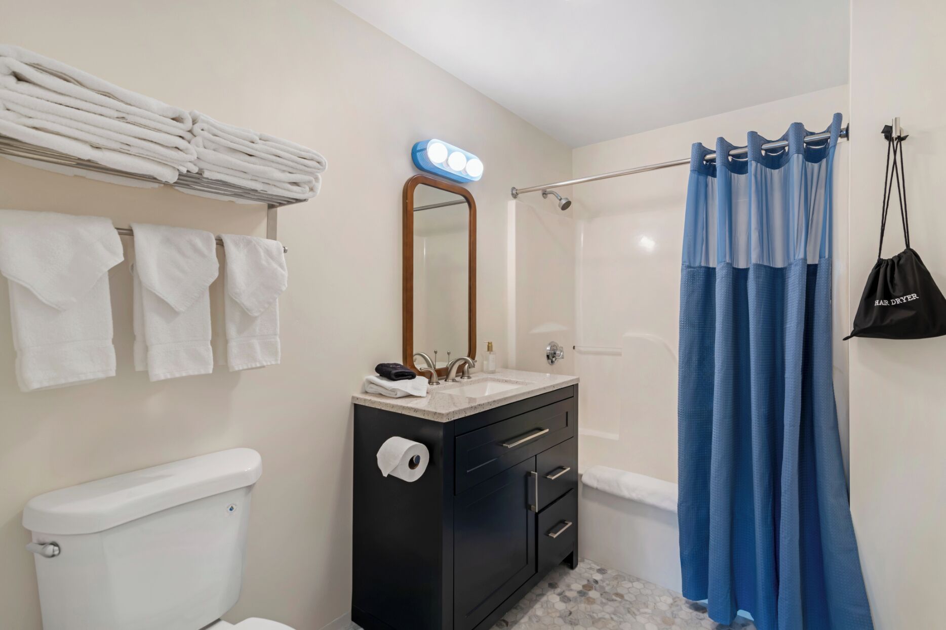 A bathroom with a toilet, sink, mirror, towel rack, and shower curtain.